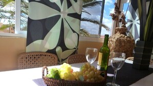 A table with a basket of grapes, a bottle of wine, and two wine glasses. - Cozy apartment in a well-kept complex with pool, only 40 meters to the beach (Corralejo)