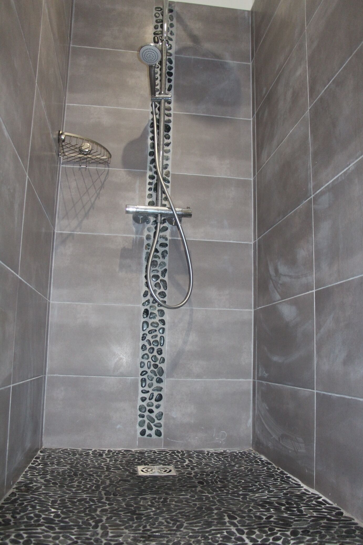 Eine Dusche mit Regendusche, Duschhandstück und fest installierter Bedienpanel.