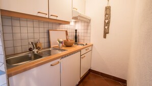 Eine kleine Küche mit weißen Schränken, einer Holzauskładung, einem Spülbecken und einem dekorativen Wandbild.