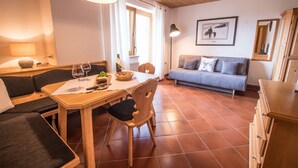 Ein gemütliches Zimmer mit Holztisch, einer Couch und einem Schrank.