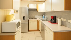Une cuisine compacte équipée d’un réfrigérateur, d’un four à micro-ondes, d’une cuisinière et d’un évier.