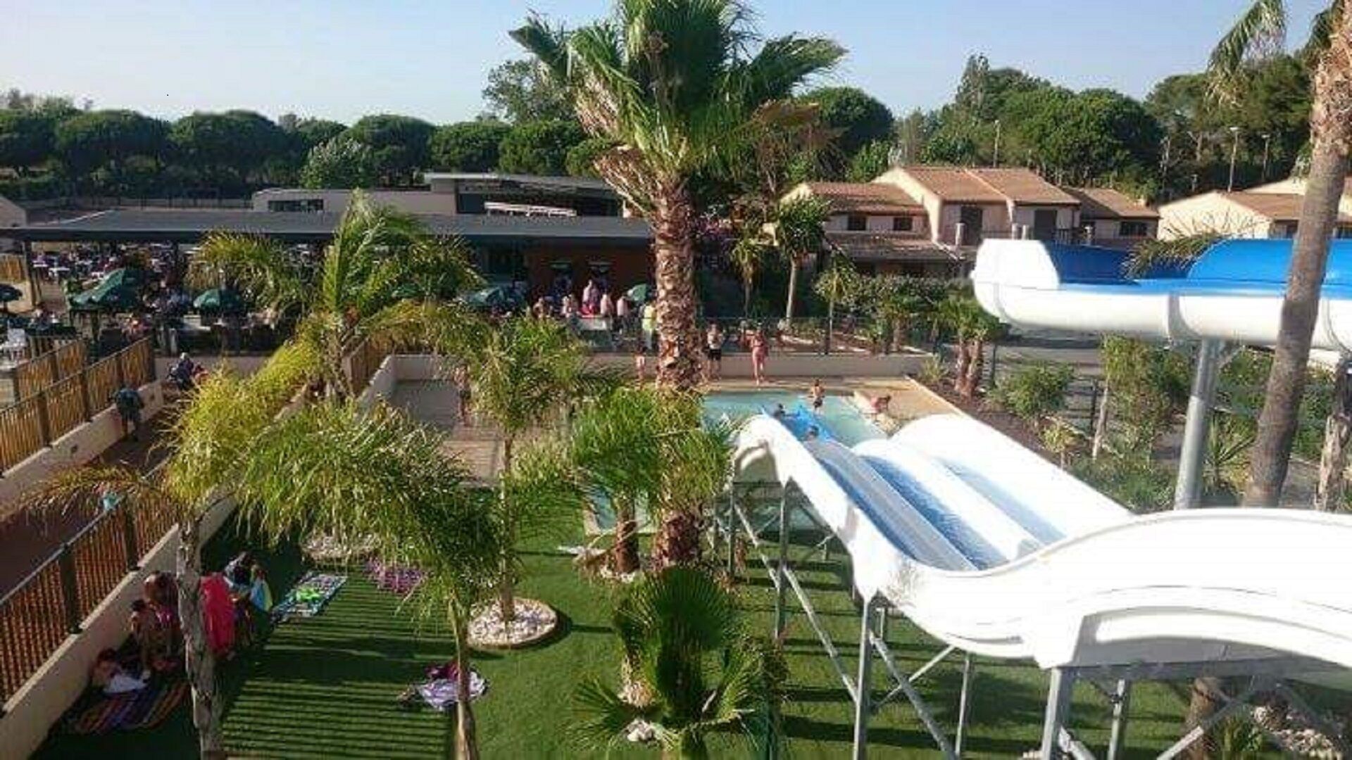 Ein Wasserpark mit großem Pool, Rutschen und Palmen.