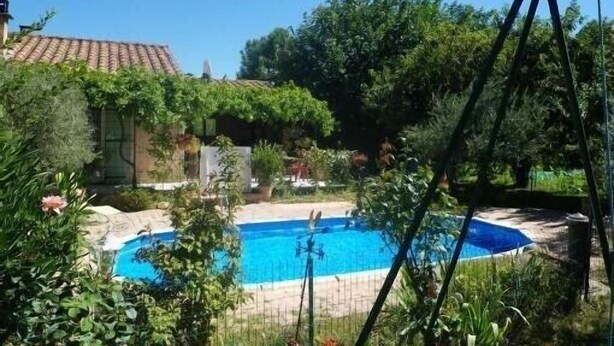 A swimming pool surrounded by lush greenery and a house with a tiled roof. - Villa sleeps 8, 2 shower rooms, summer kitchen, heated pool, shaded parking. (Mornas)