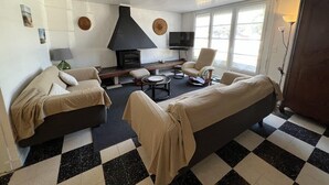 En stue med pejs, to sofaer, et fjernsyn og et stort vindue.
