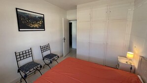 Et soveværelse med en seng, to stole, et garderobeskab, et maleri og et natbord med en lampe.