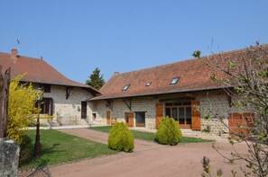 Ein Steinhaus mit einem Ziegeldach, einem gepflasterten Auffahrtsweg und einer kleinen Rasenfläche.