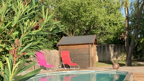 A swimming pool with a wooden deck, surrounded by greenery and a wooden fence. - The house of Elorac St Remy de Provence with private pool (Saint-Rémy-de-Provence)
