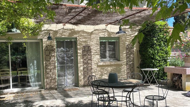 A patio area with a round table and four chairs, a small window, and a door with a screen. - The house of Elorac St Remy de Provence with private pool (Saint-Rémy-de-Provence)