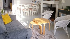 A living room with a grey sofa, a wooden coffee table, wicker chairs, a fireplace, and pendant lights.
