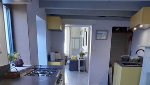 A modern kitchen with a central island, a dining area with a sofa, and a kitchen counter with appliances.