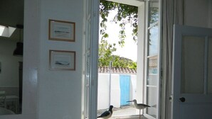A room with a window, a small table with a decorative item, and two framed pictures on the wall.