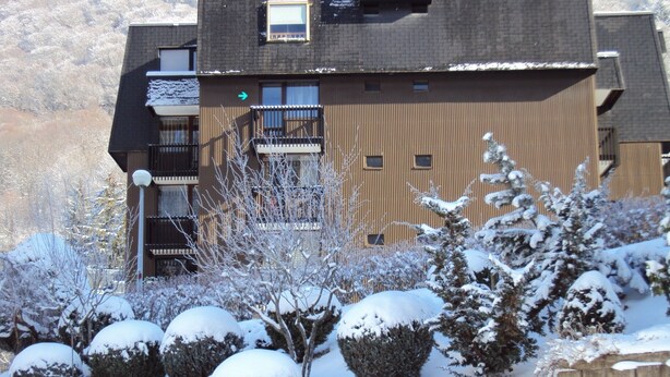 A snow-covered landscape with a building featuring multiple windows and balconies. - Studio 21m²- 2* - city center- wifi - balcony - private parking - linen included (Mont-Dore)