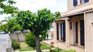 Una casa amb un porxo cobert, un arbre i un jardí petit.