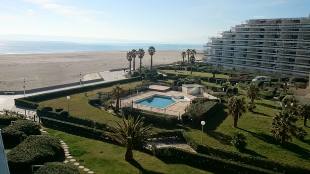 A hotel with a pool, palm trees, and a beach view. - Apartment seafront luxury building Canet Sud, parking and free WIFI (Canet-En-Roussillon)