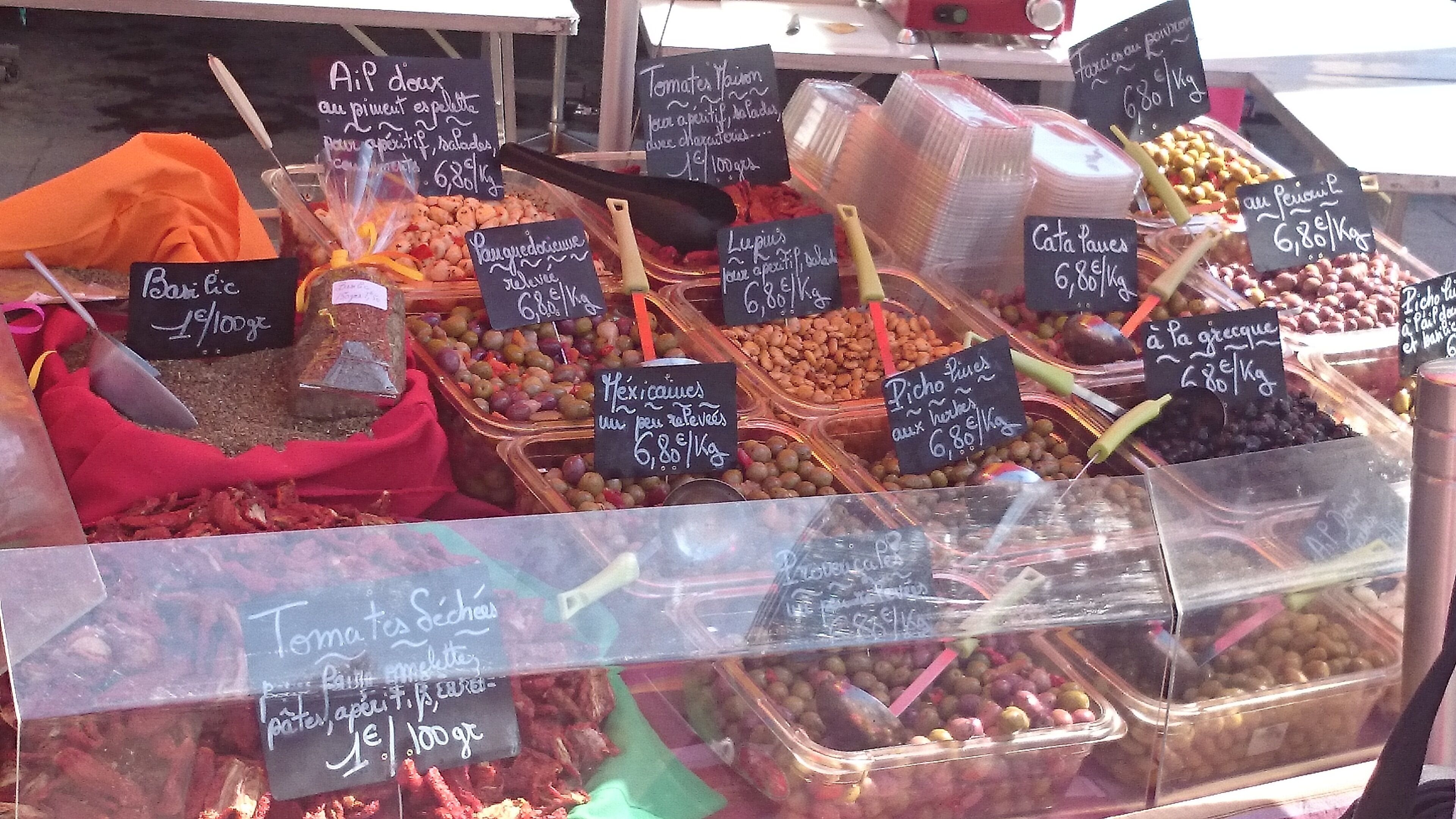 A variety of food items displayed in a market stall with price tags.