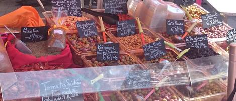 A variety of food items displayed in a market stall with price tags.