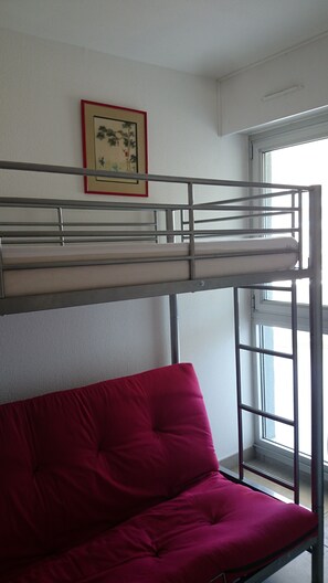A bunk bed with a red mattress and a framed picture on the wall.