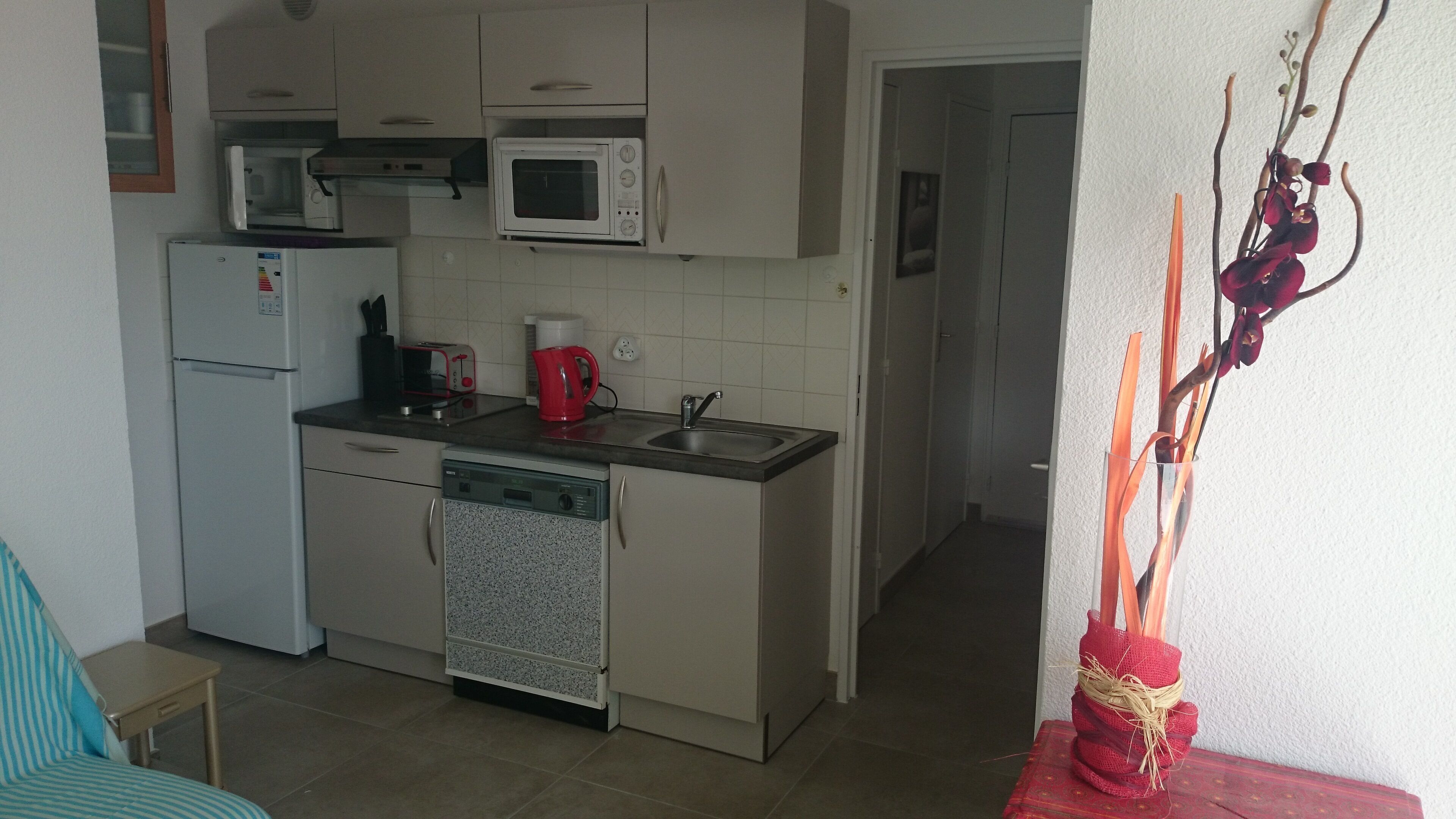 A compact kitchen with a refrigerator, microwave, toaster, and sink.