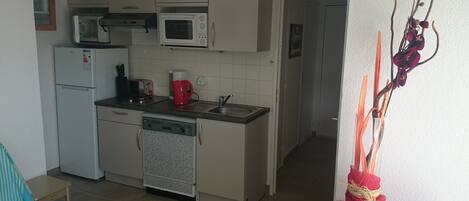 A compact kitchen with a refrigerator, microwave, toaster, and sink.