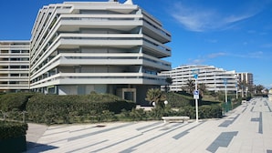A modern multi-story building with balconies, a paved walkway, and a clear blue sky. - Apartment seafront luxury building Canet Sud, parking and free WIFI (Canet-En-Roussillon)