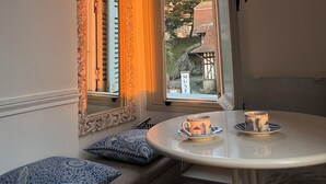 Et værelse med et vindue, et bord med en kop og en bænk med puder.