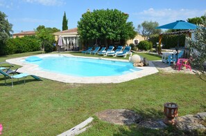 A backyard with a swimming pool, lounge chairs, and a pergola with an umbrella. - Family villa in the heart of Provence with swimming pool, garden Up to 10 people (Saint-Cannat)
