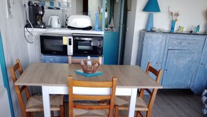 A compact kitchen with a dining table and chairs, a microwave, toaster, and a coffee maker.