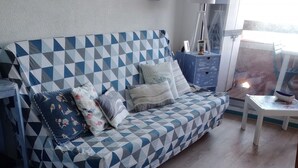A modern living room with a geometric-patterned sofa, a small table, and a view through a glass door.