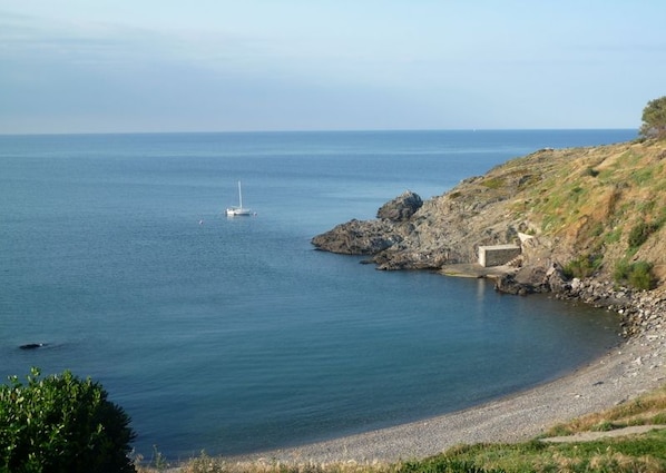 A coastal scene with a rocky shoreline, a small boat, and a building near the water. - Apartment in quiet residence, overlooking the sea, 4 persons (Port-Vendres)