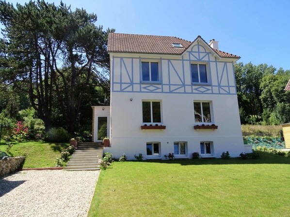 Ein zweistöckiges Haus mit einem Ziegeldach, einem Hauseingang mit Treppe und einem gepflegten Rasen.