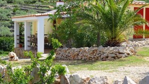 Un'area relax all'aperto riparata, con pareti in pietra e vista su un paesaggio collinare.
