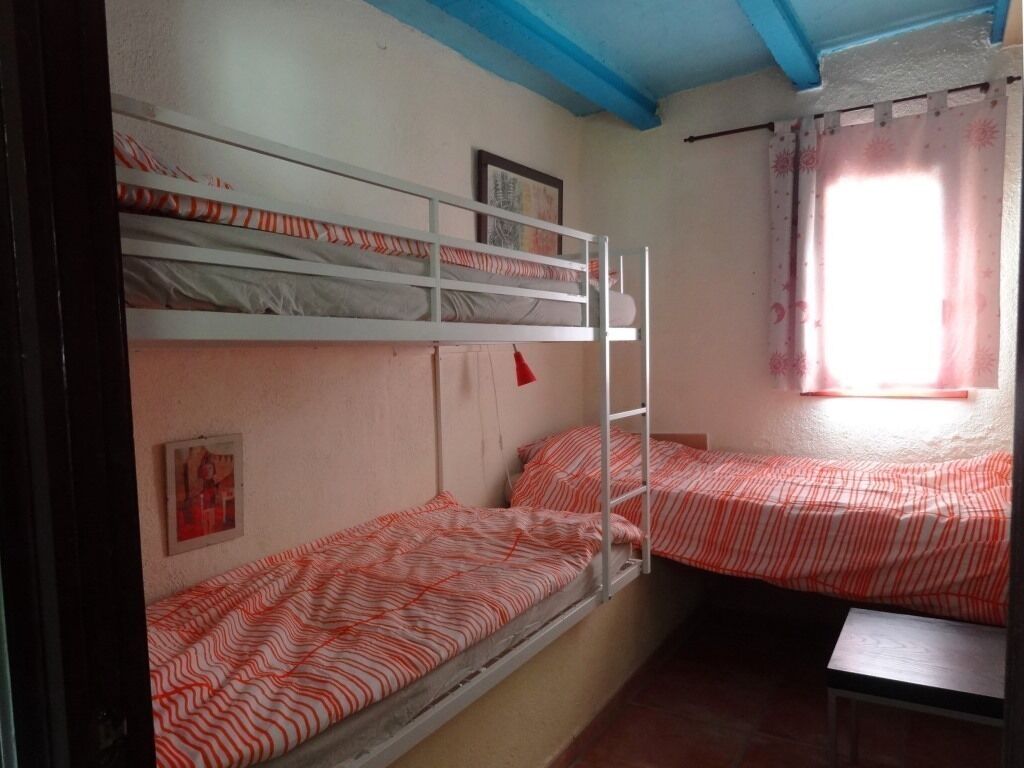 Una camera del dormitorio con letti a castello, una finestra con tende e una piccola panca.