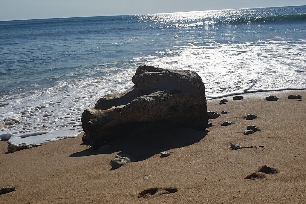 A rock formation on a sandy beach with footprints around it.