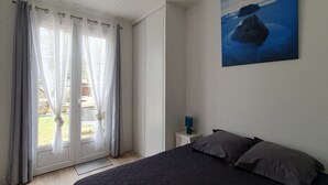Une chambre à coucher avec un lit, une table de chevet, un tableau et une porte-fenêtre coulissante avec des rideaux.