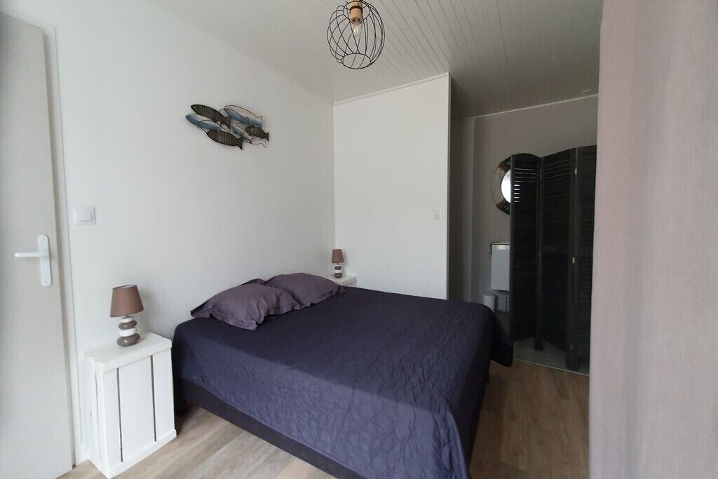 A bedroom with a bed, a nightstand with lamps, a wall art piece, and a wardrobe.