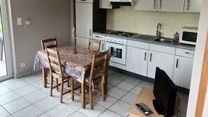 A compact kitchen with a dining table, chairs, a microwave, a stove, and cabinets.
