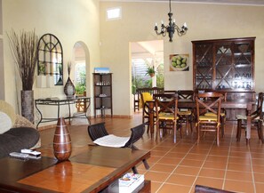 Uma sala de jantar com mobiliário de madeira, um lustre e um armário com copos.