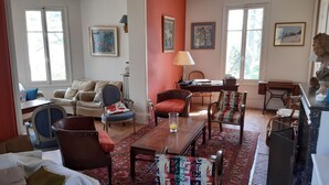 Un salon spacieux avec une grande fenêtre, un canapé, une table basse et un tapis à motifs.