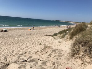 Ein Sandstrand mit Zelt und Personen.