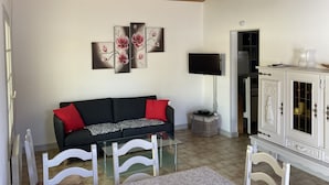 A living room with a black sofa, a flat-screen TV, and a white cabinet.