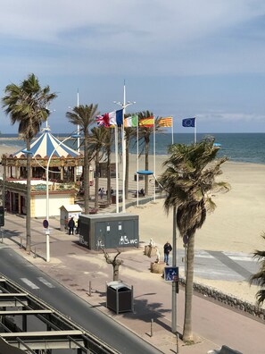 A beachside promenade with palm trees, a carousel, and flags of various countries. - Can Sol: A Cozy and Comfortable Villa in Canet Plage—Everything Within Walking Distance (Canet-En-Roussillon)