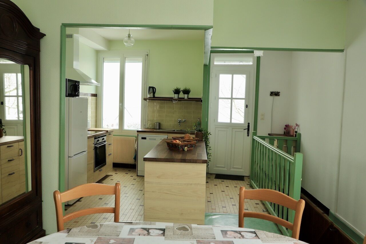 Une cuisine dotée d’un îlot central, de meubles blancs et d’un coin repas avec deux chaises.