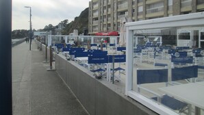 Eine Uferpromenade mit Sitzbereichen in blau gefassten Reihen, die mit "Caravel Cafe" beschriftet sind.