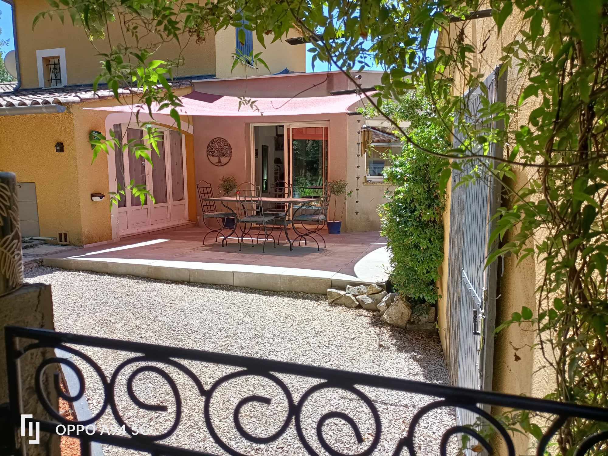 A courtyard with a dining area, including a table and chairs, surrounded by a low stone wall.