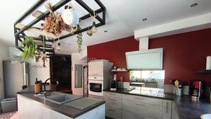 Une cuisine moderne dotée d’un îlot central, d’appareils électroménagers intégrés et d’un mur d’accent rouge.