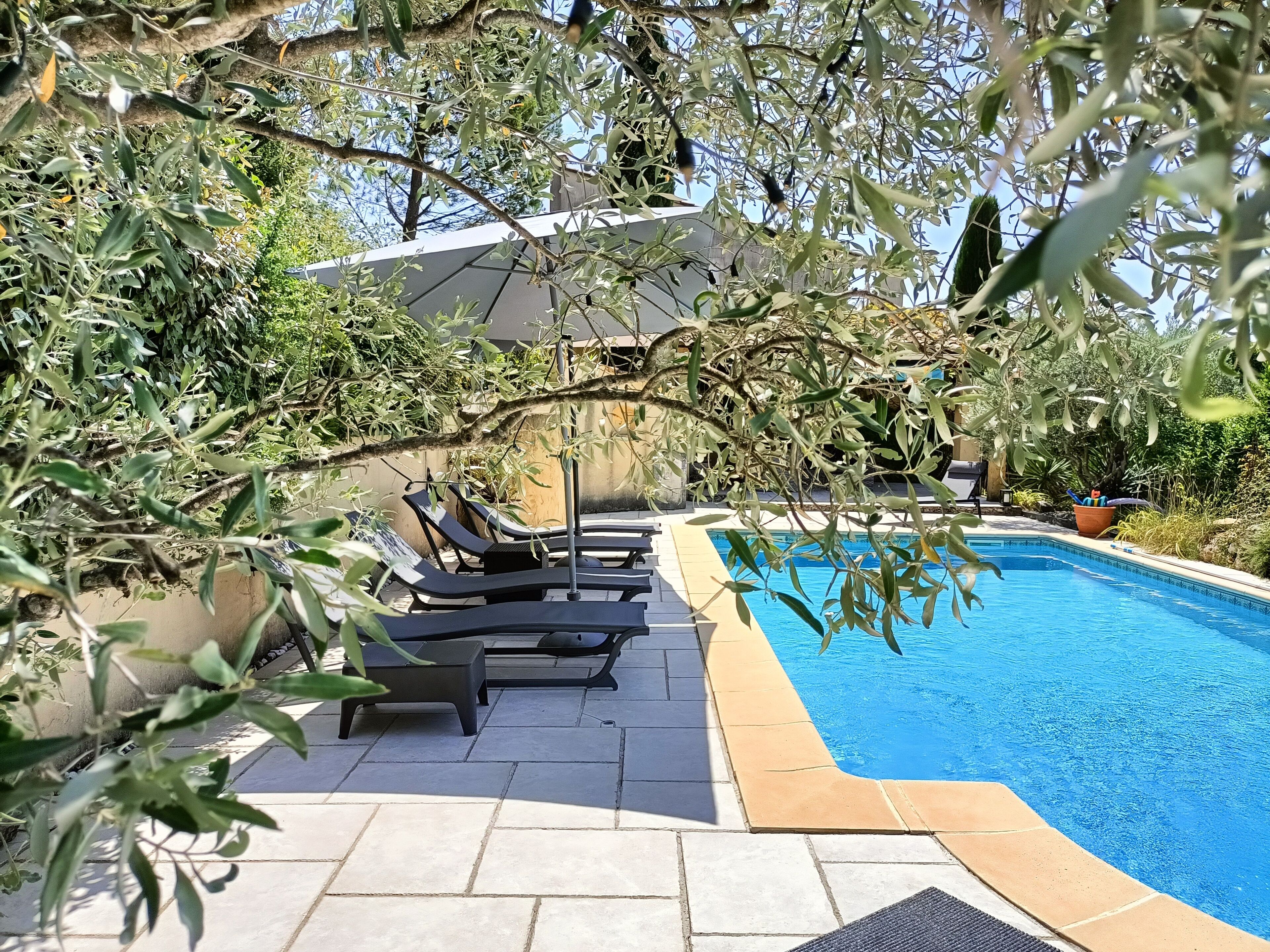 Un espace piscine avec des chaises longues et une terrasse carrelée.