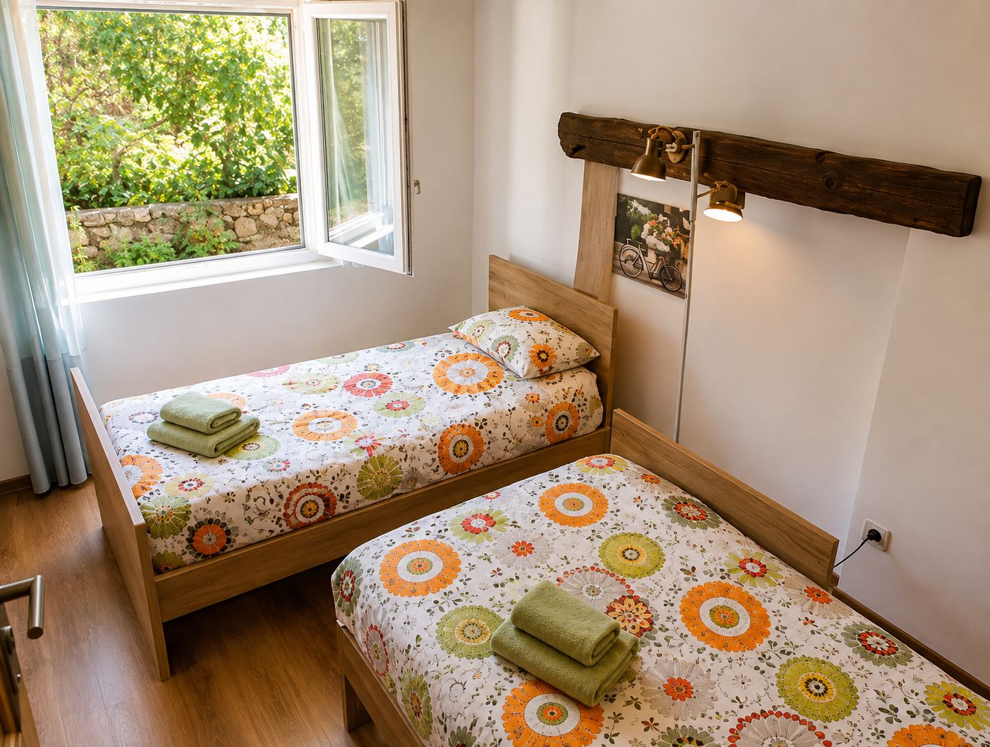 Une chambre avec deux lits simples, une fenêtre avec des rideaux, une tête de lit en bois et un luminaire fixé au mur.