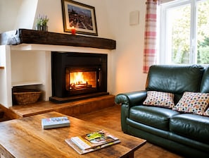 A cozy living room with a fireplace, leather sofa, and a wooden coffee table with magazines.