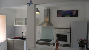 Une cuisine moderne dotée d’un four encastré, d’une hotte en acier inoxydable et d’un petit coin repas avec deux verres à vin.