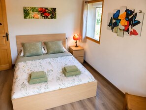 Un dormitorio con cama, mesita de noche, lámpara y decoración en la pared.